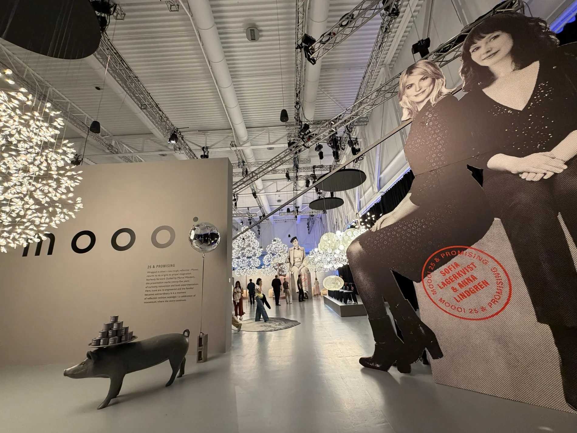 Scénographie événementielle immersive : exposition de design avec silhouettes découpées grand format et suspensions lumineuses