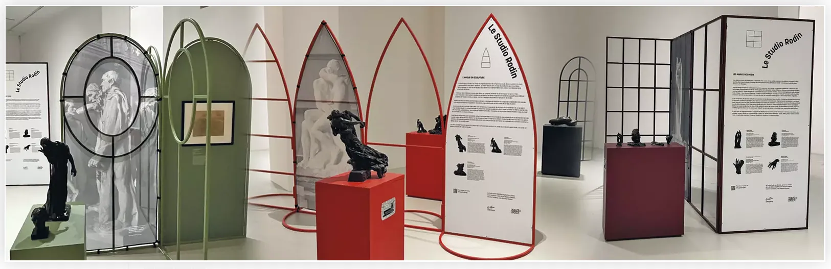 Scénographie d'exposition itinérante du Musée Rodin : arches métalliques rouges et supports d'œuvres
